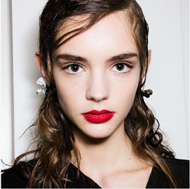 Model showing off flawless skin, red lipstick and sleek hair.